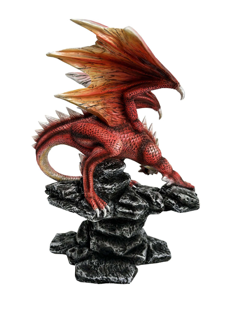 Red dragon figurine on rocky outcrop with a white background