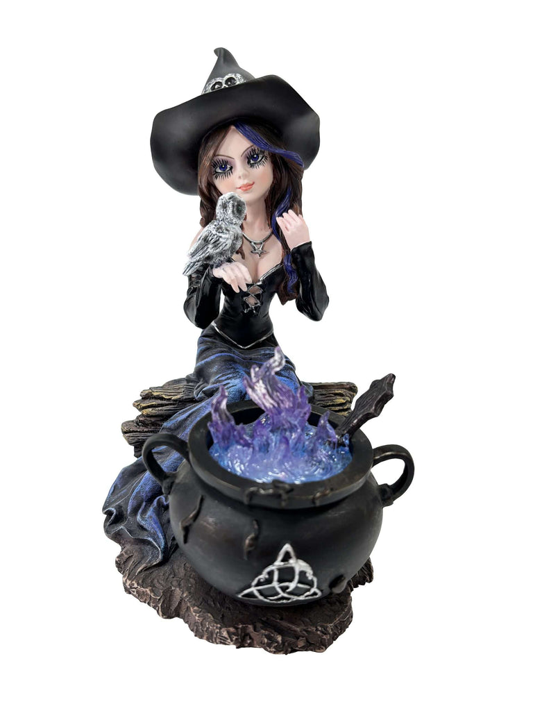 Decorative figurine of a witch with a black hat and a bird, standing over a cauldron with a blue flame on a white background.
