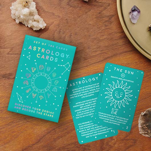 Set of astrology cards on a wooden surface with crystals around