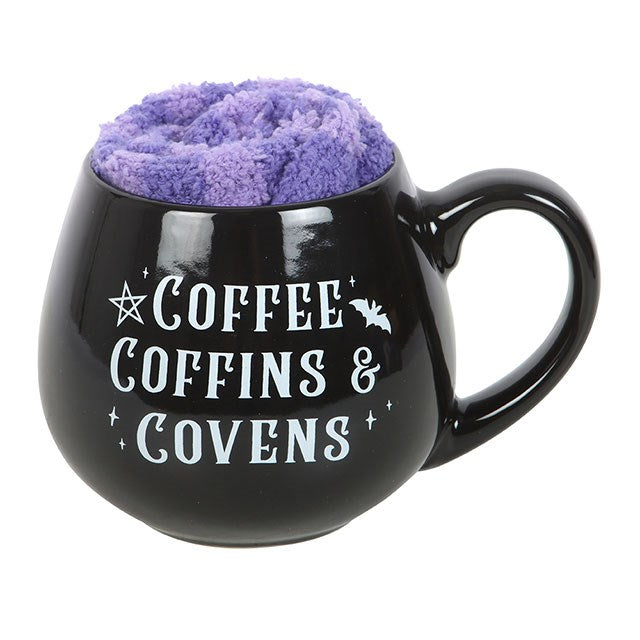 Black mug with purple contents and 'Coffee Coffins & Covens' text on a white background