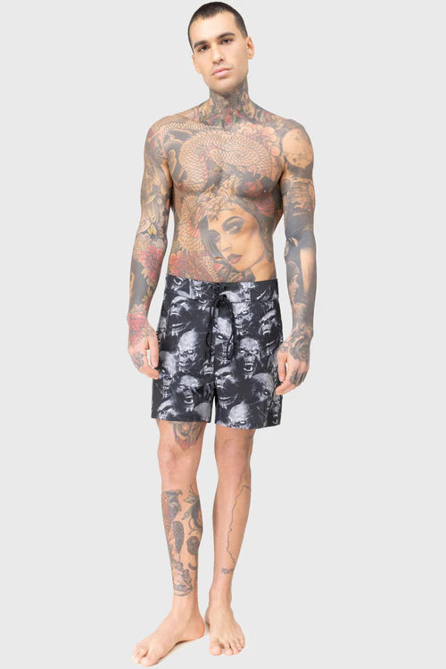 Man wearing black floral swim shorts on a white background