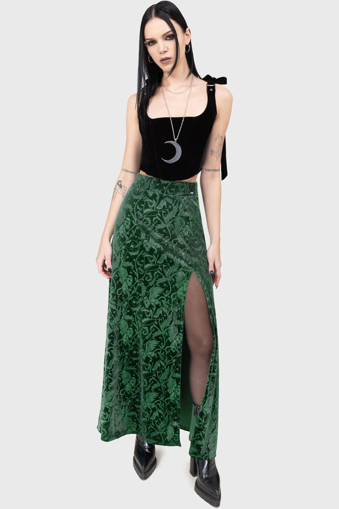 Woman wearing a black top and green patterned skirt on a white background