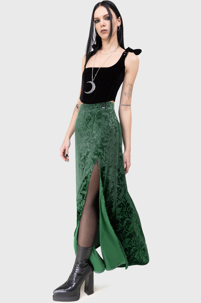 Woman wearing a black top and green velvet skirt on a white background