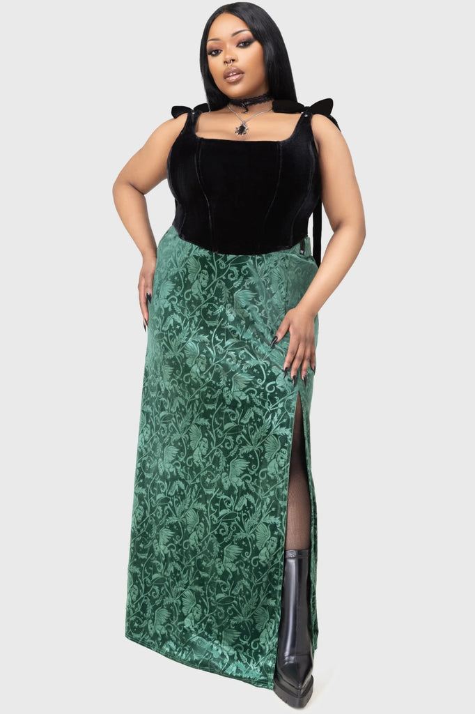 Woman wearing a black top and green patterned skirt on a white background