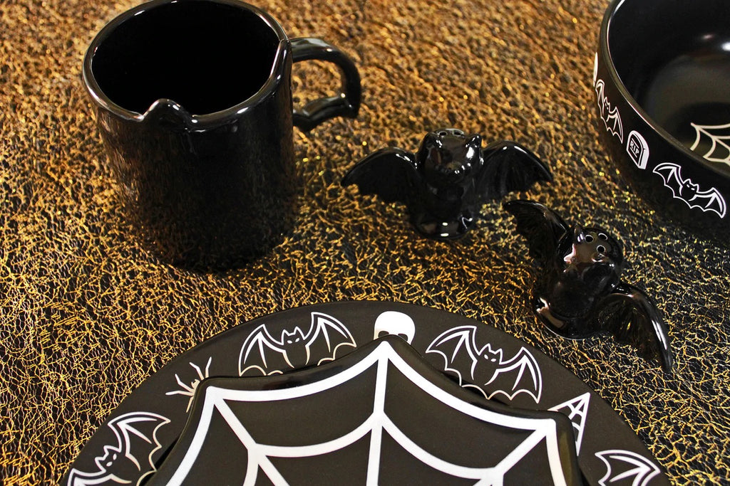 Black ceramic items with bat and web designs on a textured surface