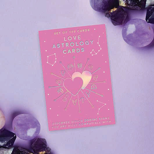Pink card with 'Love Astrology Cards' text surrounded by crystals on a light purple background