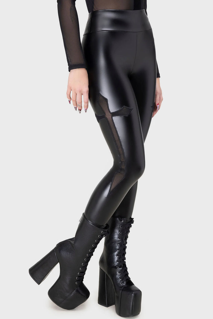 Person wearing black high-waisted leggings with mesh panels and black platform boots on a white background