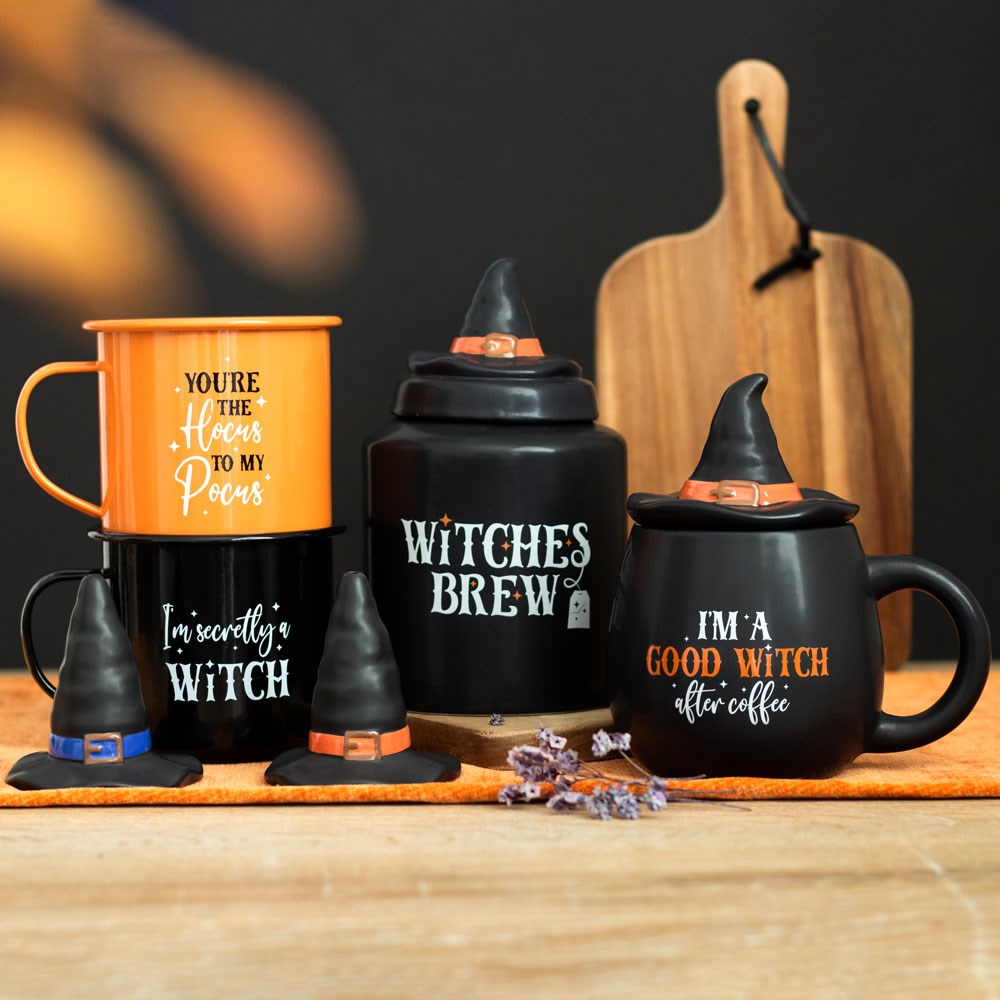 Halloween-themed mugs and containers with witch hats on a wooden surface.