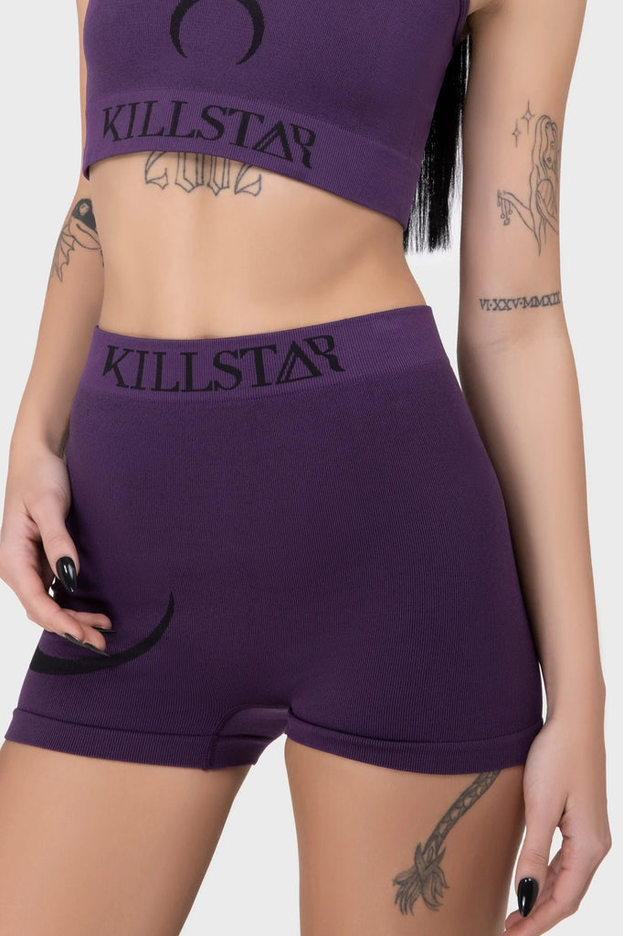 Person wearing purple 'Killstar' shorts and crop top on a white background
