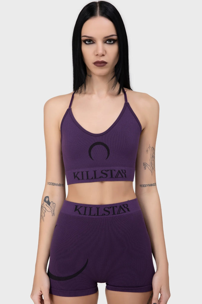 Woman wearing a purple 'Killstar' sports bra and shorts set on a white background