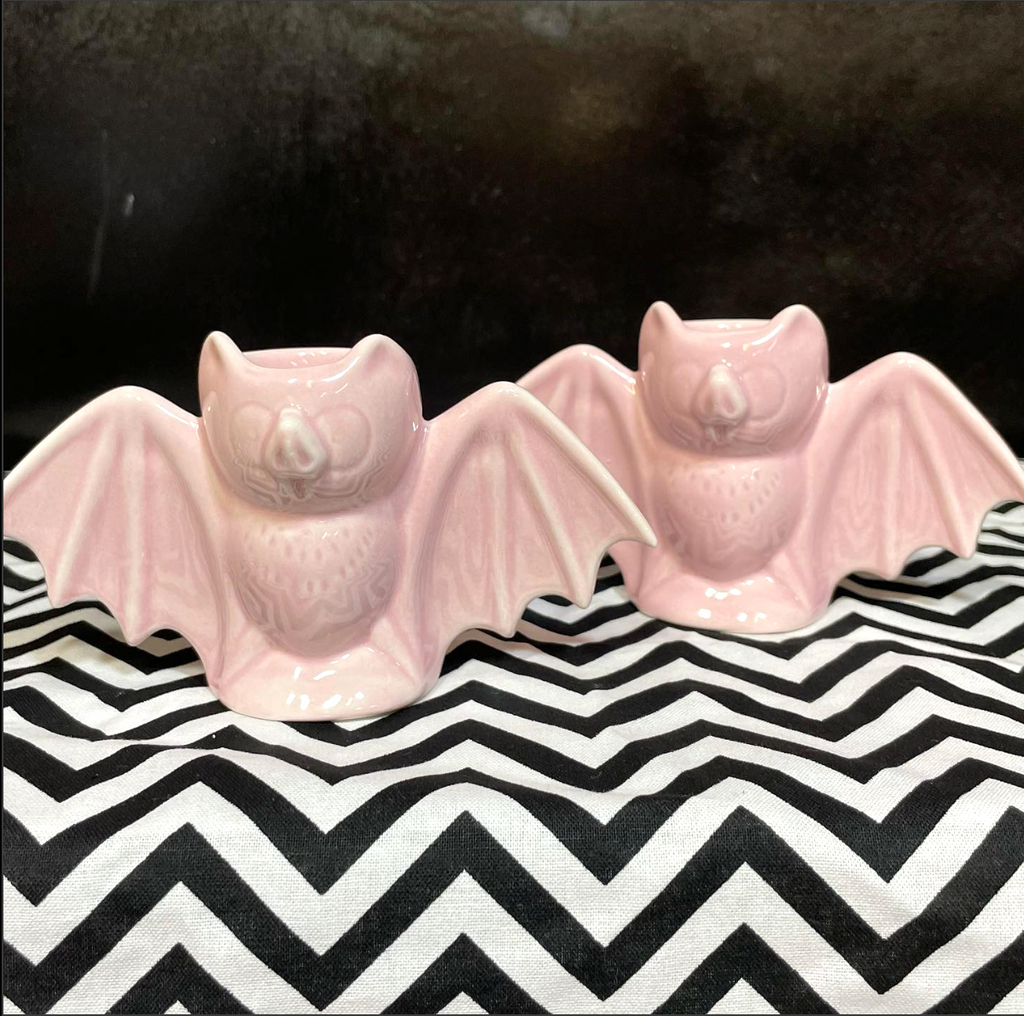 Two pink ceramic bats on a black and white zigzag patterned surface.