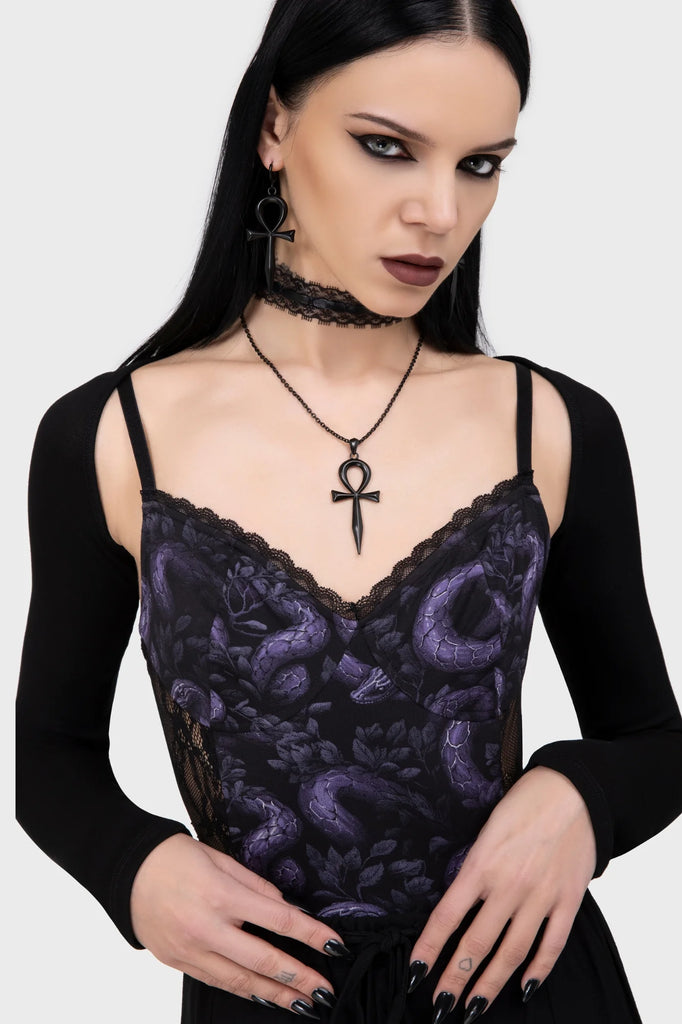 Woman wearing a black lace top with a purple pattern and an ankh necklace on a white background