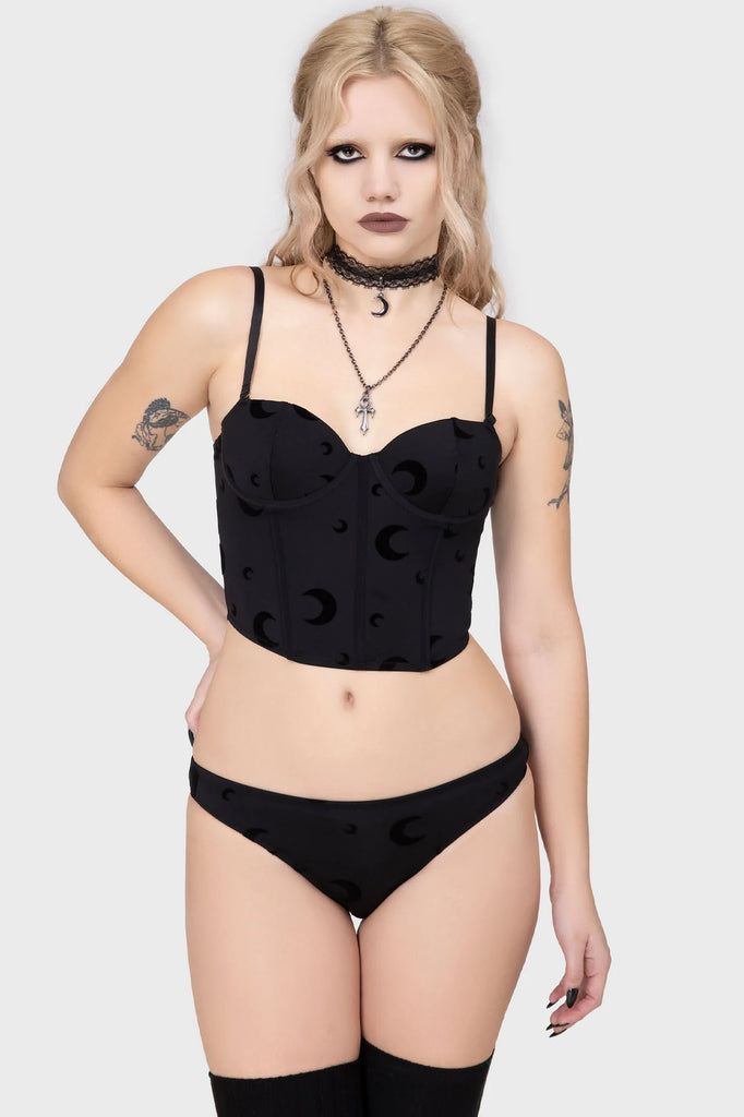 Woman wearing a black lingerie set with moon patterns on a white background