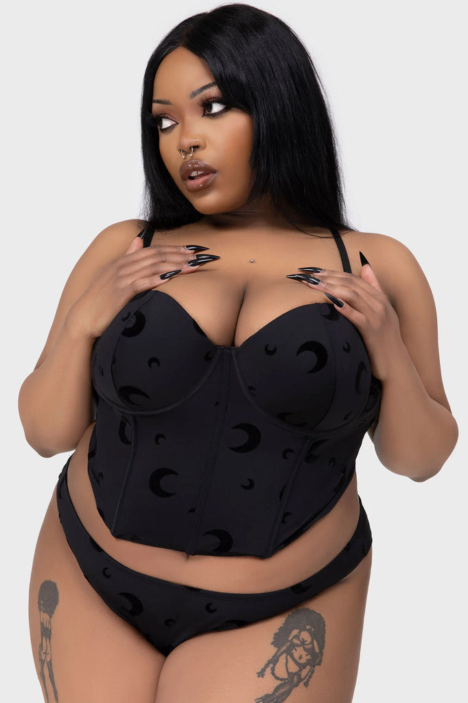 Woman wearing a black lingerie set with a plain background