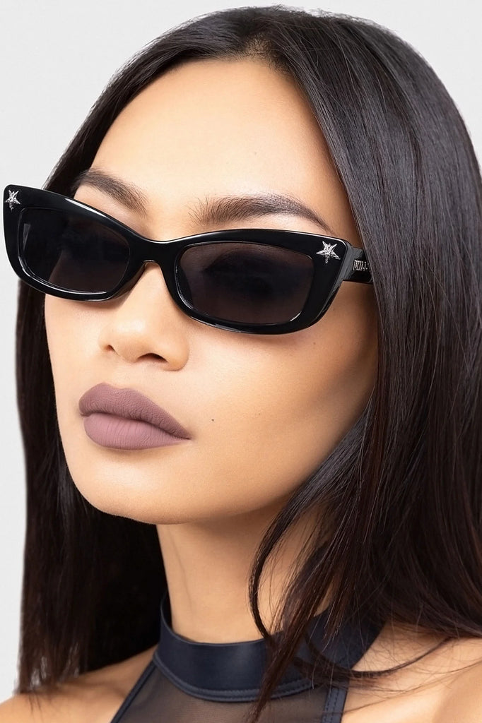 Woman wearing black cat-eye sunglasses with a neutral background