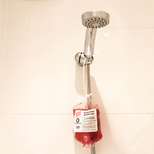 Shower head with a red bag attached on a tiled wall