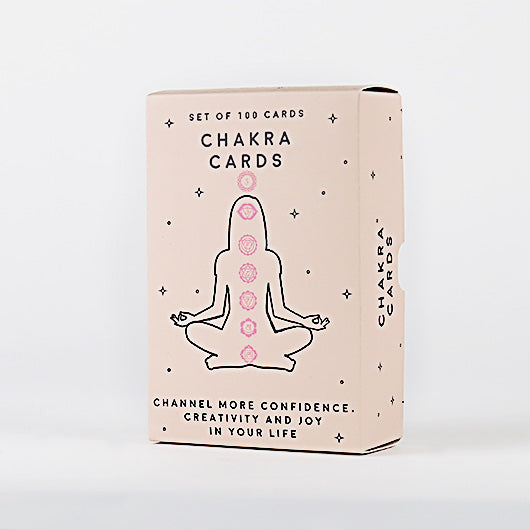 Box of Chakra Cards with a silhouette of a person in meditation pose on a light pink background.