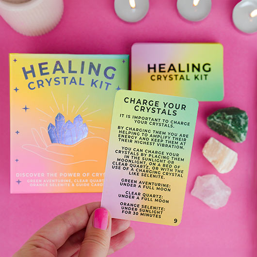 Healing crystal kit with cards and crystals on a pink background