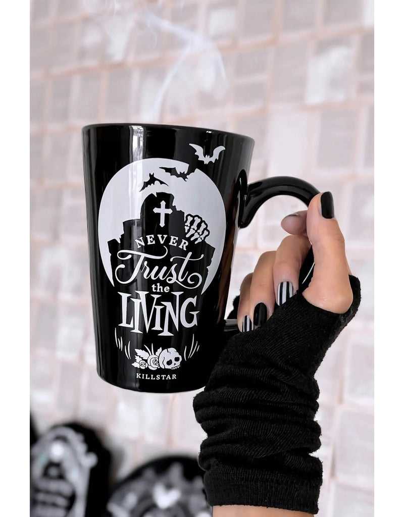 Black mug with Halloween-themed design held by a person wearing a black sleeve.