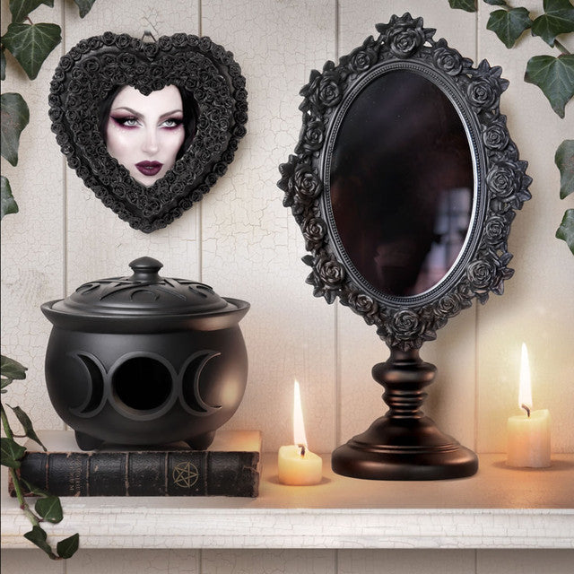 Decorative items including a black heart-shaped mask, mirror, black pot, and candles on a shelf.